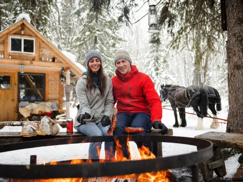 Couple enjoying a fire during a sleigh ride at B&T Adventures in Smithers BC