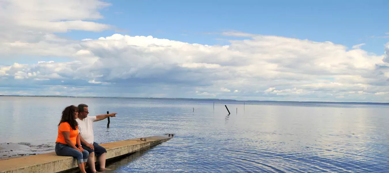 A couple sits on the dock by a lake in Plamondon Lac La Biche