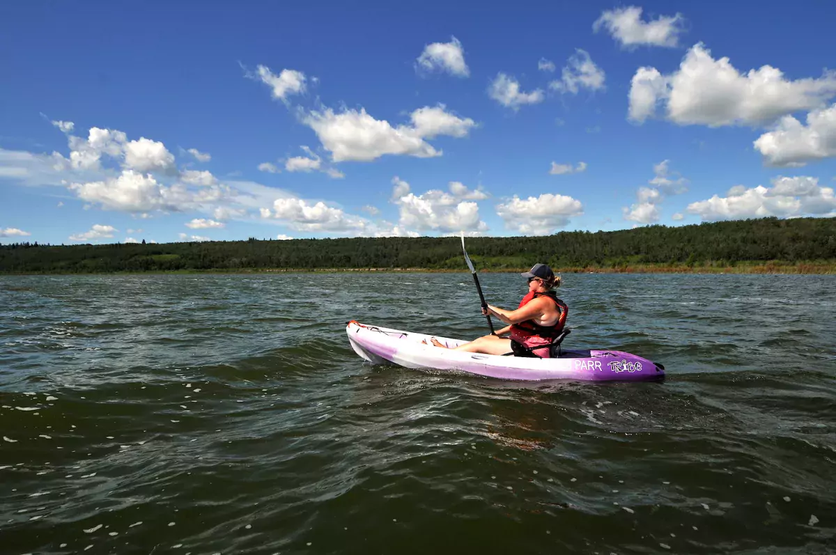 A woman kayaks on a lake in MD Bonnyville