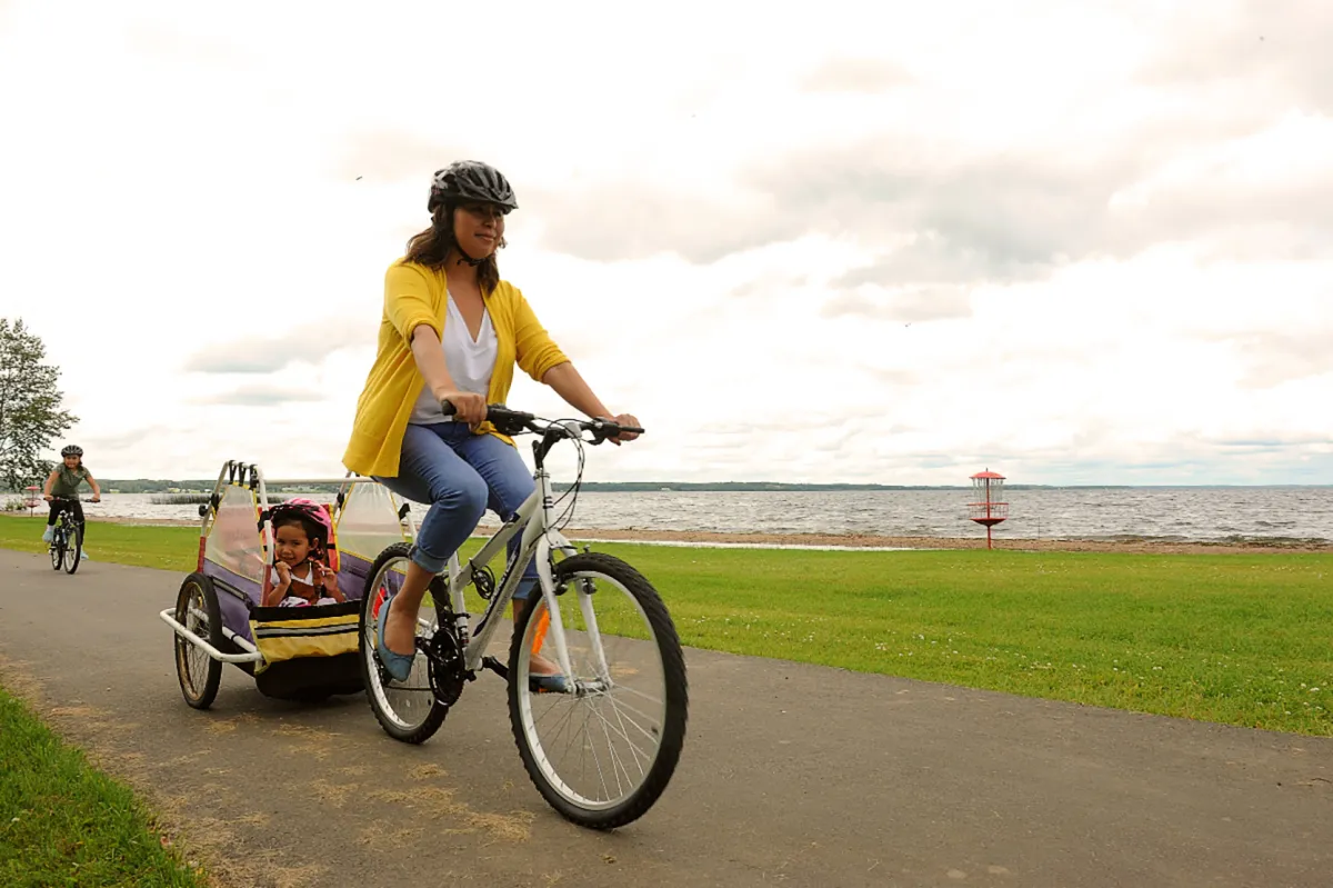 A woman and child bike along a path in McArthur Park in Lac la Biche