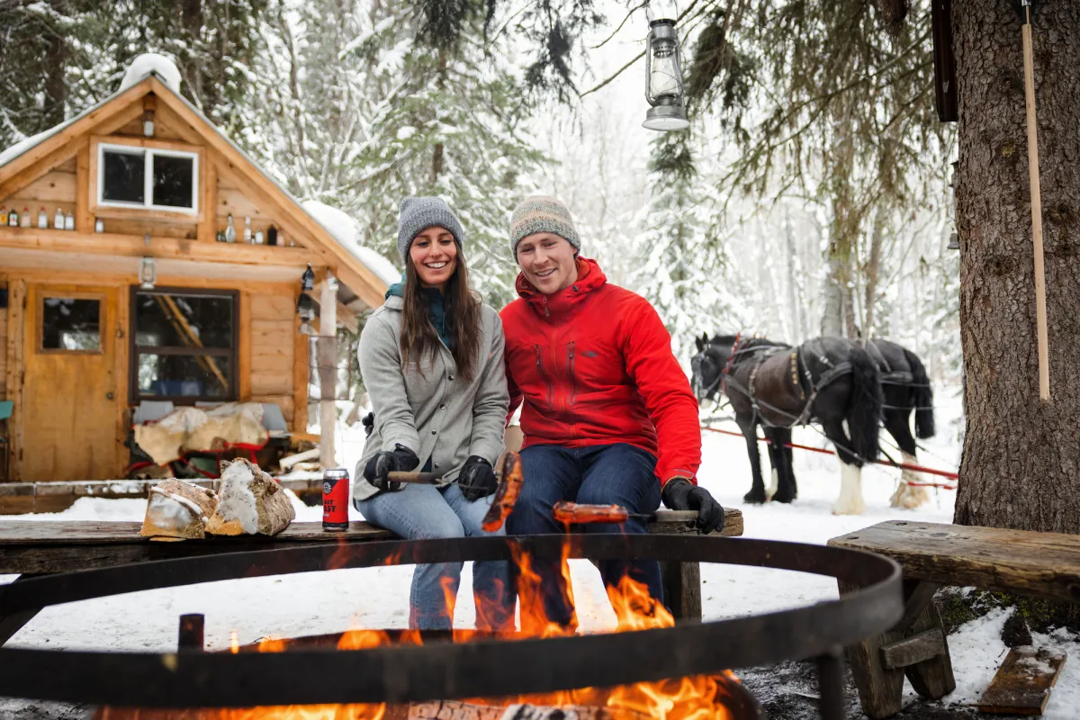 Couple enjoying a fire during a sleigh ride at B&T Adventures in Smithers BC