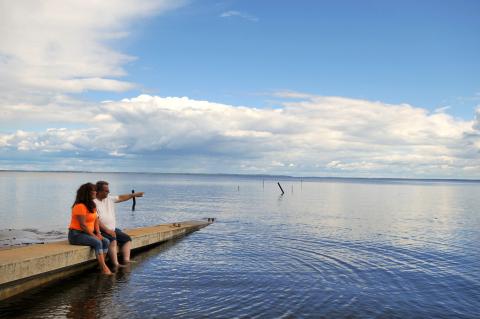 A couple sits on the dock by a lake in Plamondon Lac La Biche