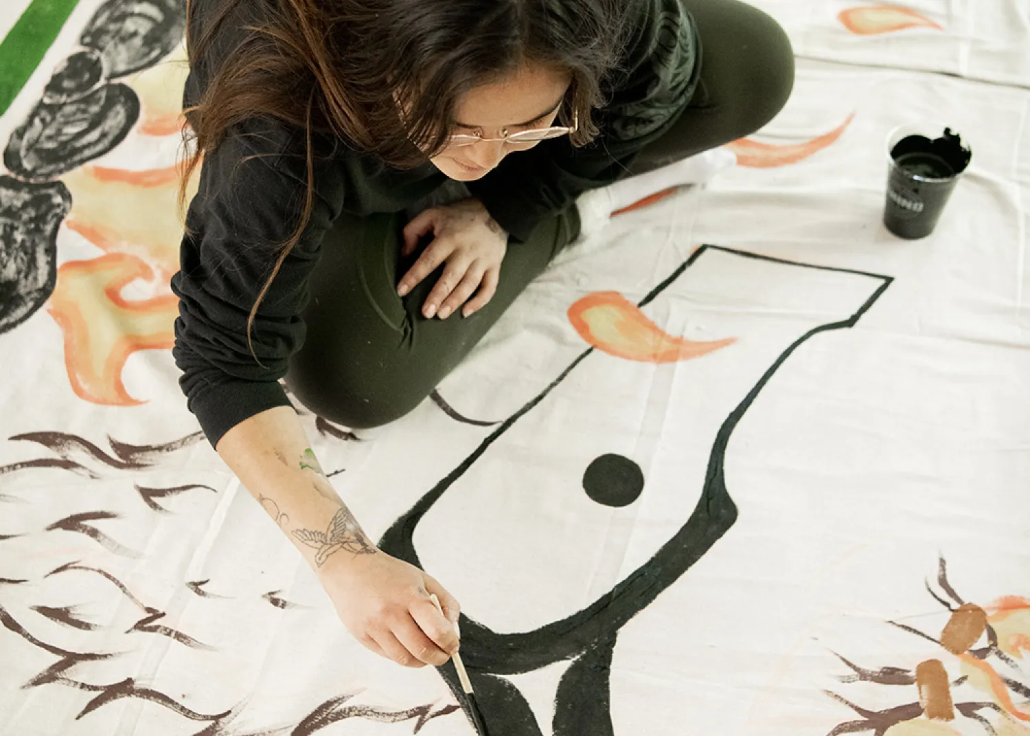 Ivy Cargill-Martin working on large scale Tla-o-qui-aht curtains that will be on display in the Tin Wis Conference Center, one of the many highlights of the naaʔuu evenings.